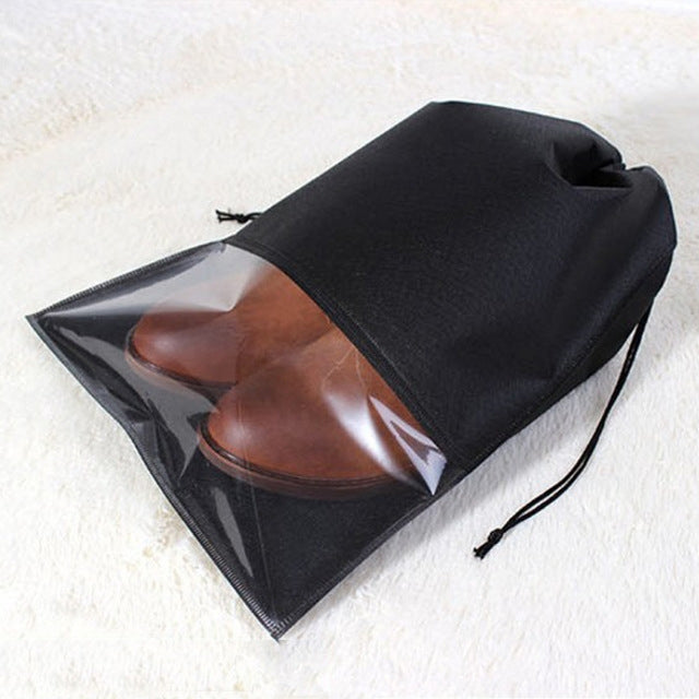 Black drawstring shoe storage bag with clear window, holding brown shoes