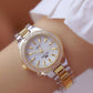 Women’s round watch on wrist with white dial, rhinestone bezel, and metal link bracelet