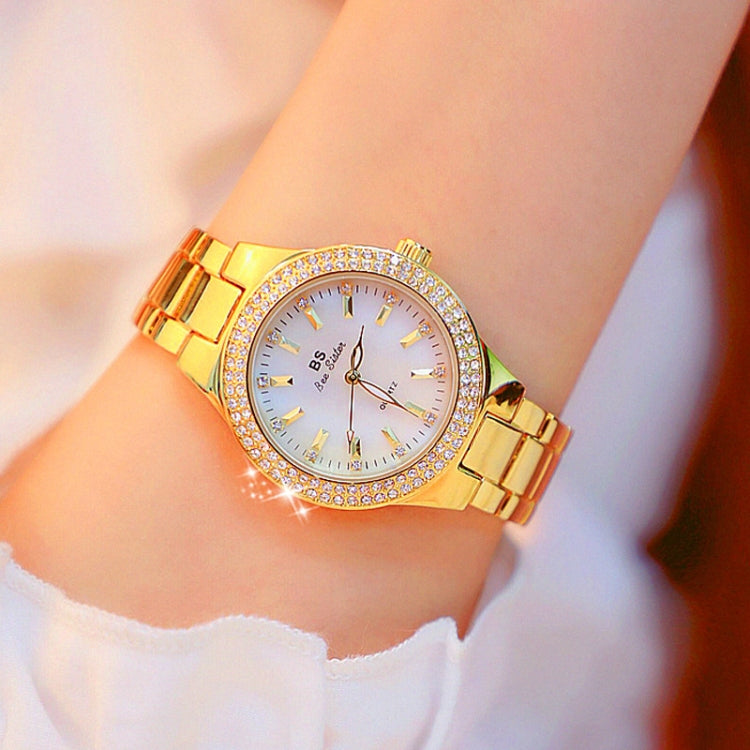 Women’s gold-tone round watch with white dial, jeweled bezel, and metal link bracelet