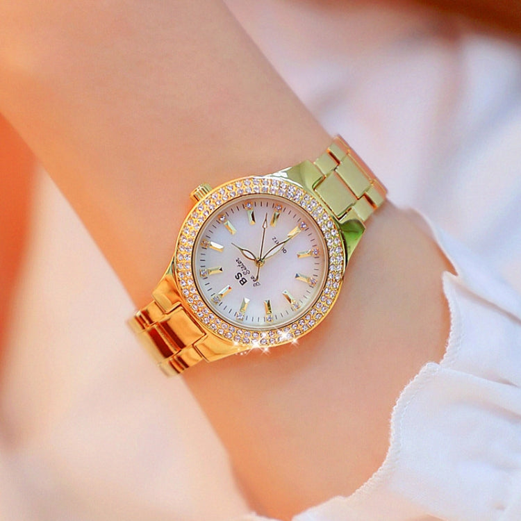 Women’s gold-tone round watch with white dial, rhinestone bezel, and linked bracelet