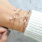 Bracelet set on wrist: thin gold chains with crystal hoop and pink charm links