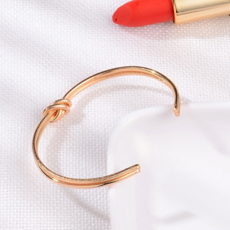 Rose-gold open cuff bracelet with small round clasp and smooth hinged band
