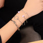 Silver-tone multilayer bracelet set on wrist with pink heart charms and crystal hoop