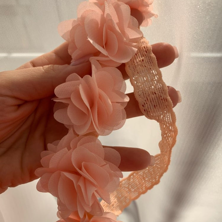 Peach-pink flower headband close-up with rosette blooms on netted elastic band