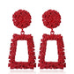 Red geometric trapezoid long dangle earrings with textured round tops and cutout frame