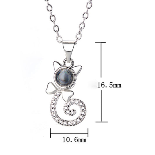 White metal projection pendant necklace with round blue disc and heart swirl charm, crystal accents