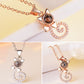 Rose gold projection pendant necklace with round dark disc and heart swirl charm, crystal stones