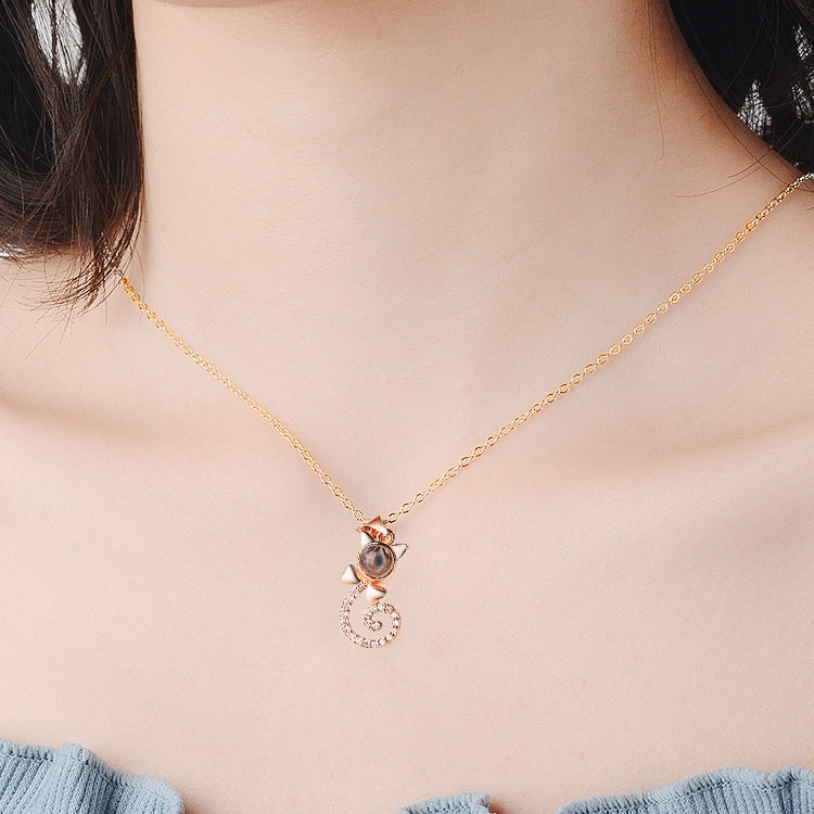 Rose gold projection pendant necklace with small round disc and heart swirl charm, crystal accents