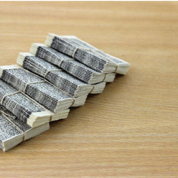 Miniature stack of gray printed newspaper bundles bound with twine