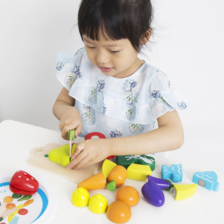 Child playing with fruit and vegetable cutting toy set on a tabletop