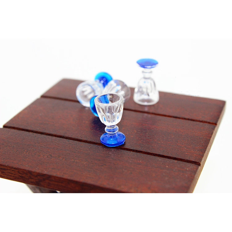 Mini transparent goblet glass with blue base on a wooden surface