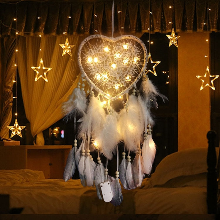 White heart dream catcher wall hanging with hanging beads, feathers, and warm string lights