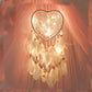 Heart dream catcher hanging with white feathers and warm fairy lights along the web
