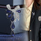 Butterfly knot brooch with blue teardrop dangles worn on dark blazer lapel