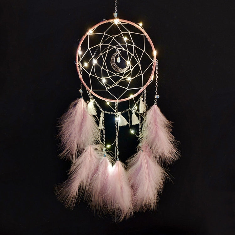 Pink dream catcher wall hanging with hoop web, dangling chains, feather fringe, and warm string lights