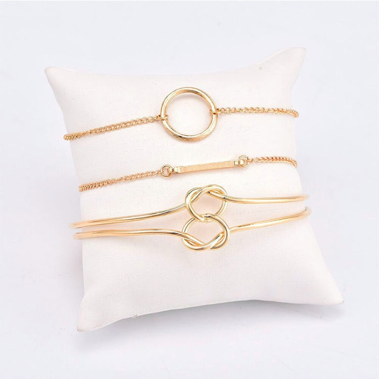 Gold-tone chain bracelet set with ring and double-knot loop detail, flat lay