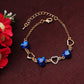 Gold-tone heart charm bracelet with blue crystals and heart toggle clasp