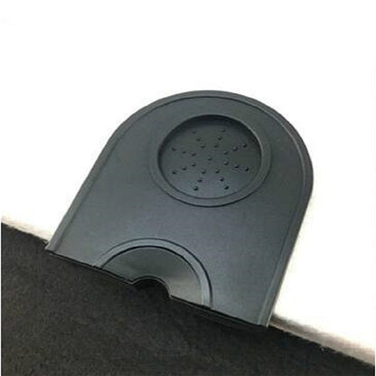 Non-slip corner coffee pad in dark gray/black with raised circular textured insert.