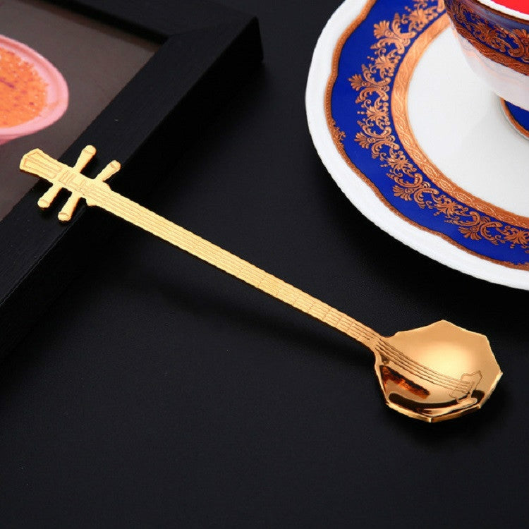 Rose gold guitar-shaped stainless steel coffee mixing spoon on a dark background
