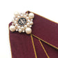 Maroon fabric bow-knot close-up with pearl beads and decorative center pin