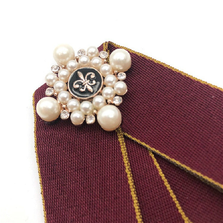 Maroon fabric bow-knot close-up with pearl beads and decorative center pin