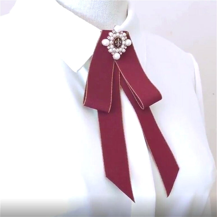 Maroon bow-knot brooch on a white shirt collar, pearl flower center with hanging tails