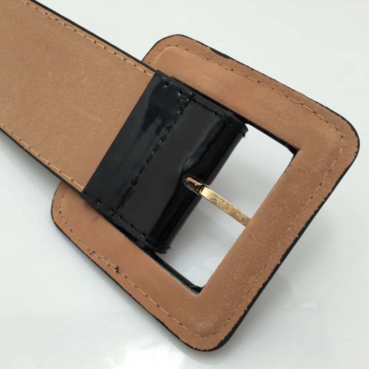 Wide belt with tan strap and square black buckle, close-up view