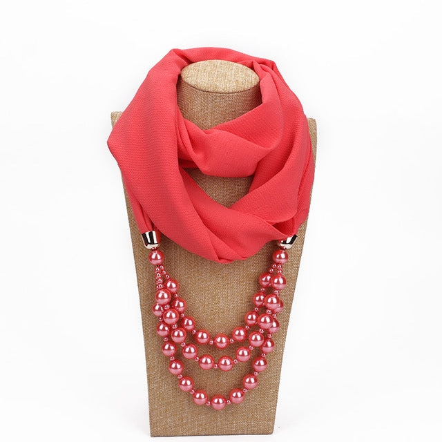 Red scarf with imitation pearl bead necklace, layered pink-red beads at the neckline.