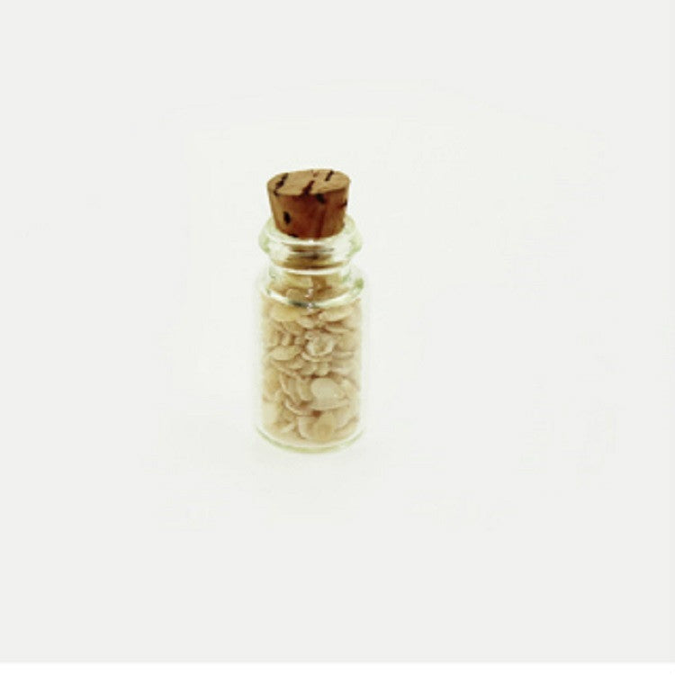 Mini glass food bottle with cork, clear body filled with pale tan chips