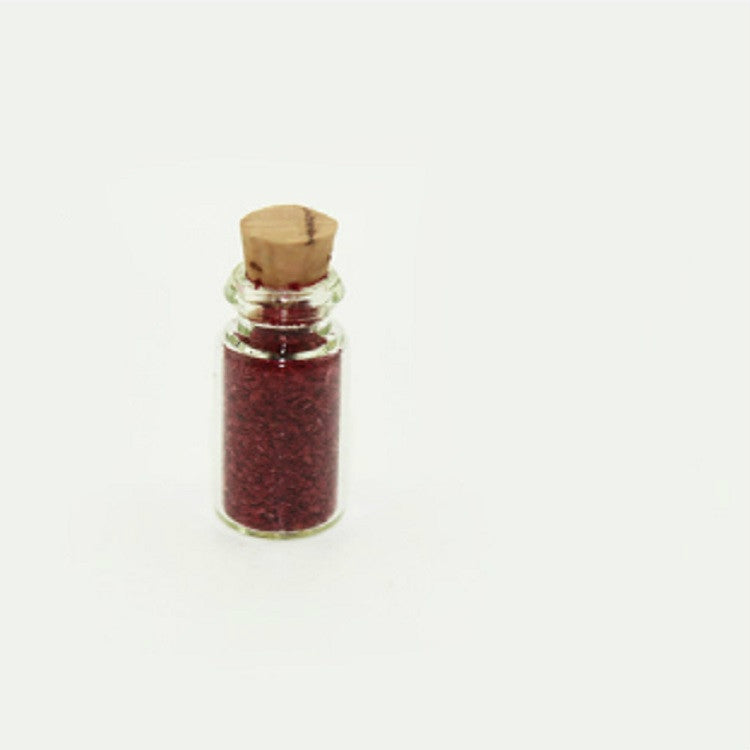 Mini glass food bottle with cork, clear body filled with dark red granules