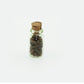 Mini glass food bottle with cork, clear body filled with dark brown chips