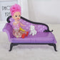 Purple doll sofa with accessories on seat, tufted back, black curved legs