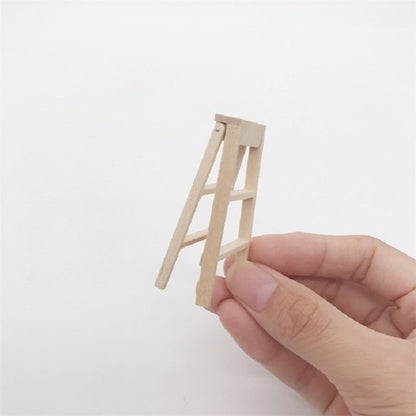 Miniature wooden ladder for 1:12 dollhouse, held in hand, light wood color