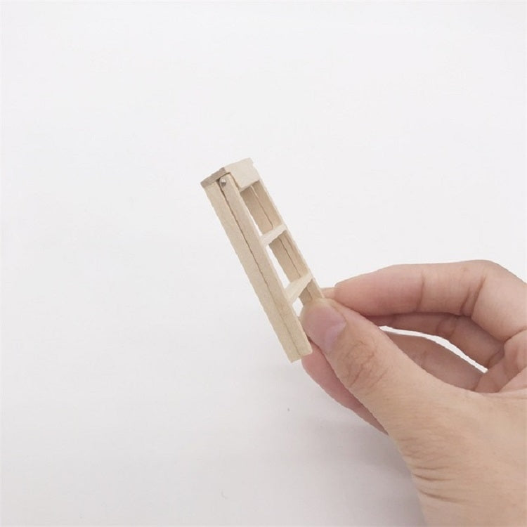 Miniature wooden ladder tilted in hand, small scale for dollhouse display
