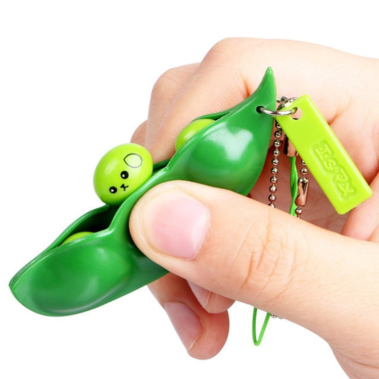 Green extrusion pea keychain pod with face charm, keyring, and chain in hand