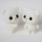 Two white bear doll figurines side by side, glossy black eyes and tiny pink cheeks
