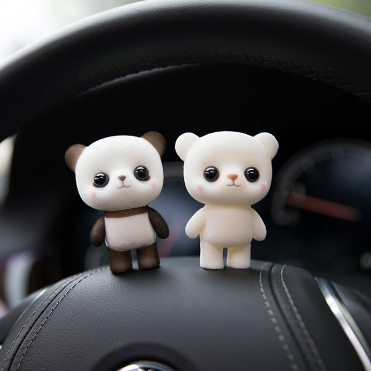 Two small white bear dolls on a dark car seat, with glossy black eyes