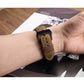 Brown leather watch band with stitched holes and metal buckle, worn on wrist.