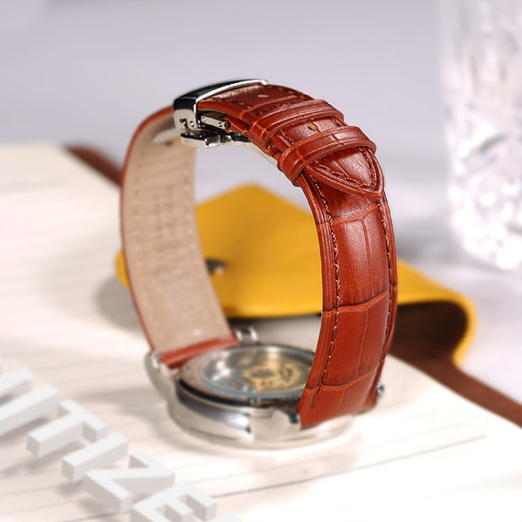 Cognac leather watch band with metal clasp on wrist, stitched crocodile texture