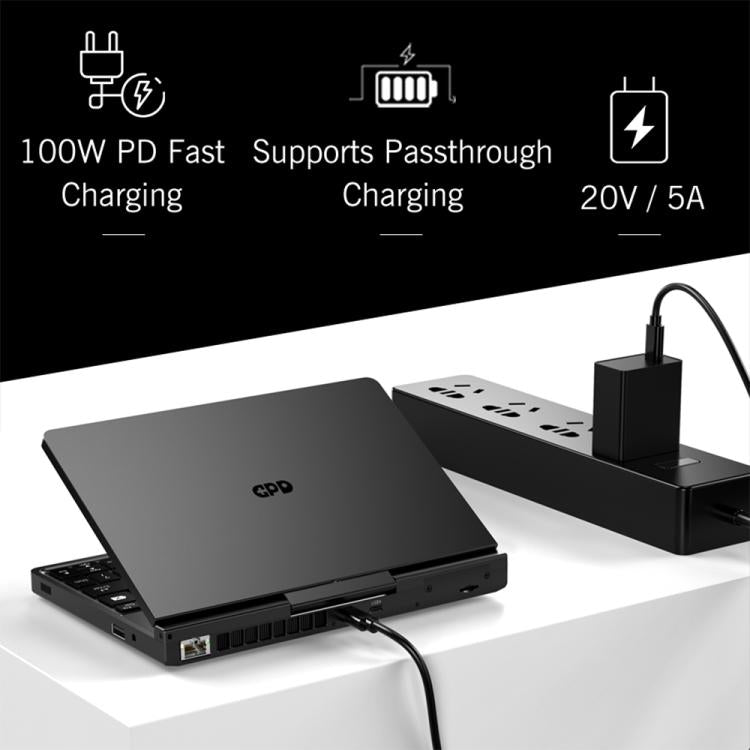 Handheld gaming PC on a stand with charging adapter cable connected, black