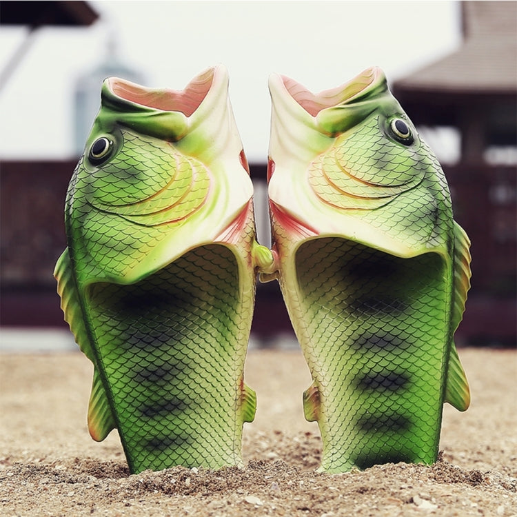 Pair of green fish-themed sandals standing on sand, open toe slip-on style.
