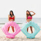 Two shell-shaped inflatable swimming rings in pink and light blue on beach sand