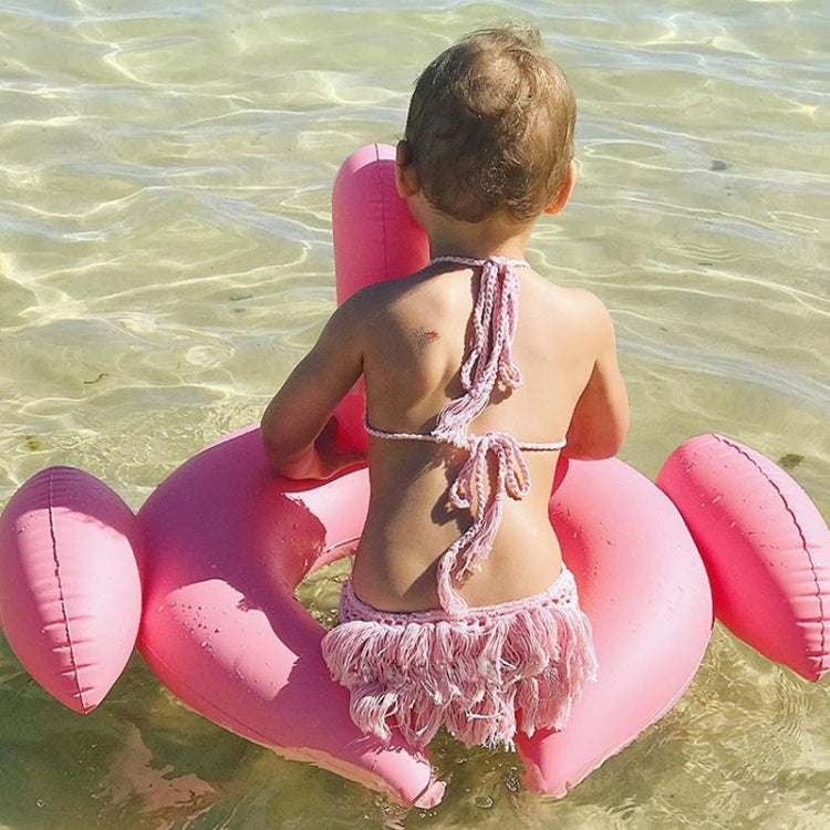 Pink flamingo inflatable pool float seen from behind on kids at the beach