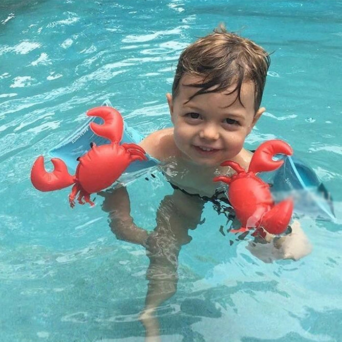 Child wearing red crab-shaped inflatable arm floats in clear blue pool water