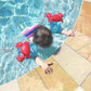 Child near the pool wearing red inflatable crab arm floats