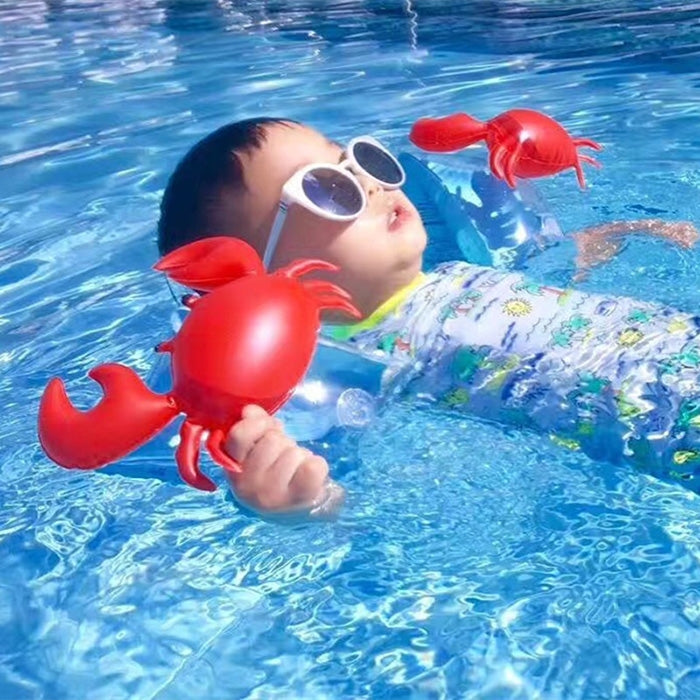 Child in pool wearing red crab-shaped inflatable arm floats