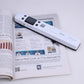 White handheld document scanner placed over an open printed page.