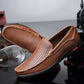Brown perforated leather loafer close-up with round toe, metal bit, and black rubber sole.