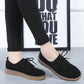 Black suede lace-up casual shoes with flat sole and tan trim, side view