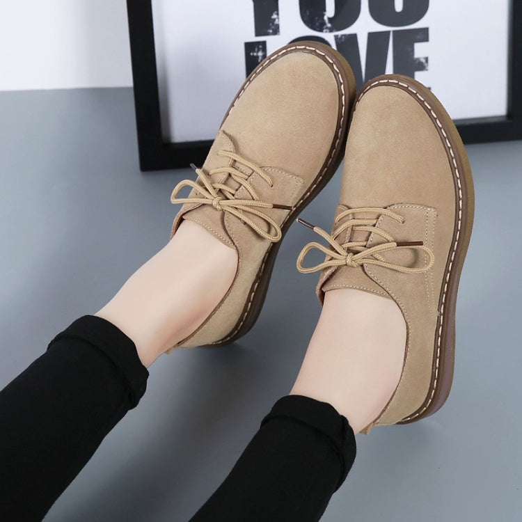 Tan suede lace-up casual shoes with flat sole and decorative lace eyelets.